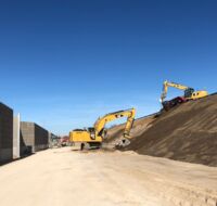 Bagger arbeiten an einem Hang neben einer Schallschutzwand.